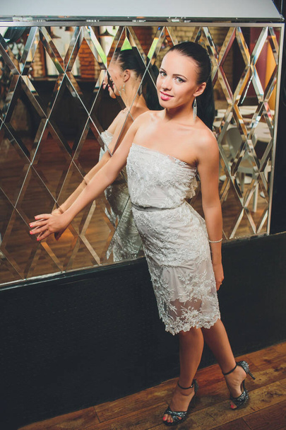 pretty woman in evening dress , with hair style posing near a restaurant bar, looking in camera. - Zdjęcie, obraz