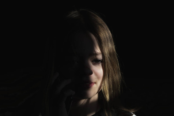 Portrait photo of a young girl on a dark background - Valokuva, kuva