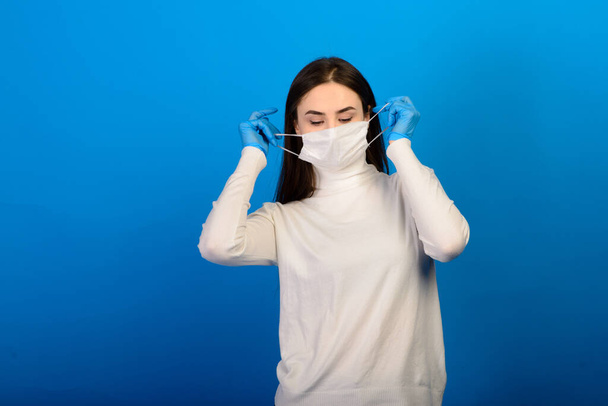 Chica en guantes médicos vestido con una máscara médica en su cara en un fondo. Covid-19 - Foto, Imagen