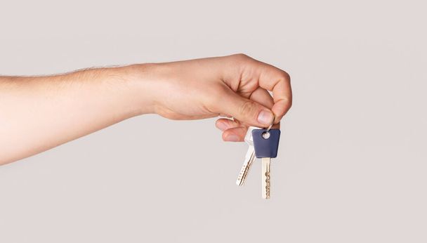 Male hand holding house keys on light background, closeup. Panorama - Фото, изображение