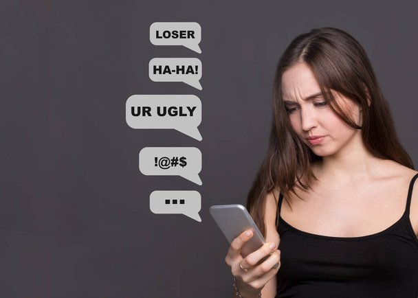 Kyberšikana. Smutné běloška čte obtěžující textové zprávy na smartphonu, šedé pozadí. Koláž - Fotografie, Obrázek