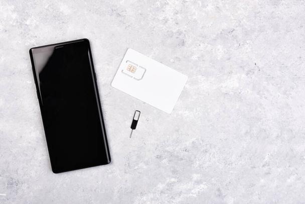 Smartphone and mobile SIM card on a marble background. Copy space for your text - Fotografie, Obrázek