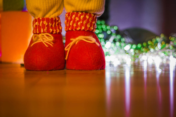 Czerwony but Bożonarodzeniowe buty na rustykalnej drewnianej podłodze na tle girlandy, tło świąteczne. - Zdjęcie, obraz