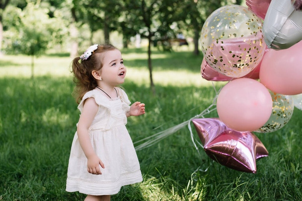 Portret młodej szczęśliwej mamy trzymającej córeczkę i uśmiechającej się w parku. Szczęśliwego Dnia Matki! - Zdjęcie, obraz