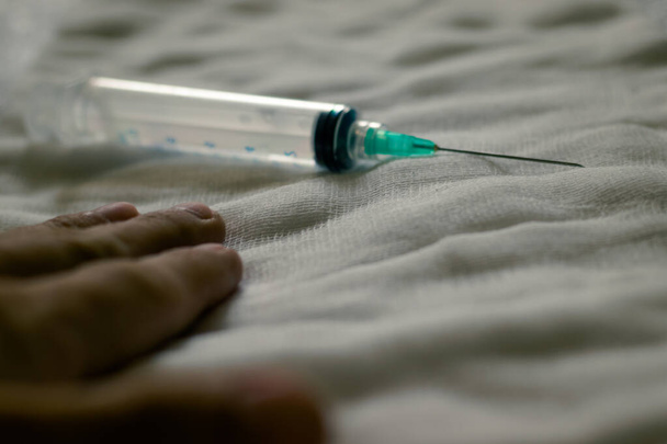 Syringe and needle and a human hand on a white gauze. Vaccine for the virus. Search for a vaccine. - Фото, зображення