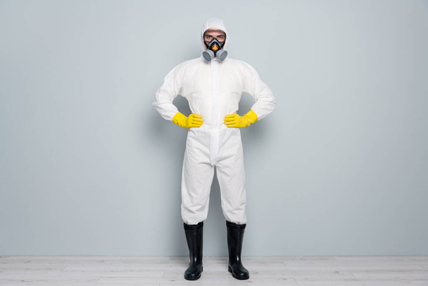 Full length photo of professional guy disinfectant watch public places clean disinfection wear white hazmat protective suit goggles mask gloves gumboots isolated grey color background - Foto, immagini