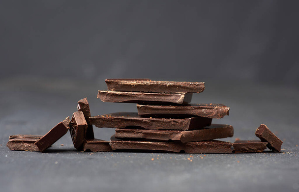 шматочки чорного шоколаду на чорному тлі, солодкий десерт, крупним планом
 - Фото, зображення