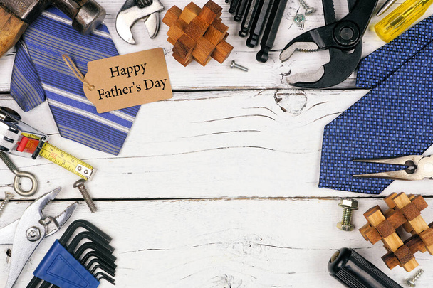 Happy Fathers Day Geschenkanhänger mit Rahmen aus Geschenken, Krawatten und Werkzeugen auf weißem Holzhintergrund. Draufsicht mit Kopierraum. - Foto, Bild