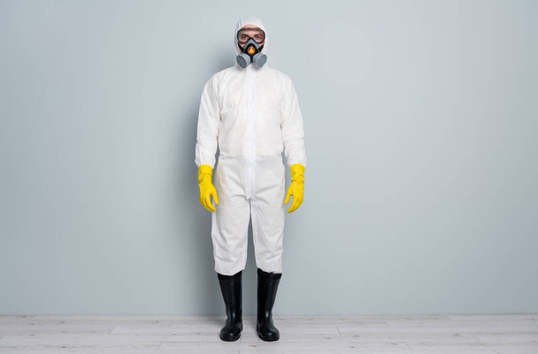 Full length photo of professional guy disinfectant watch public places clean disinfection wear white hazmat protective suit goggles mask gloves gumboots isolated grey color background - Foto, Imagem