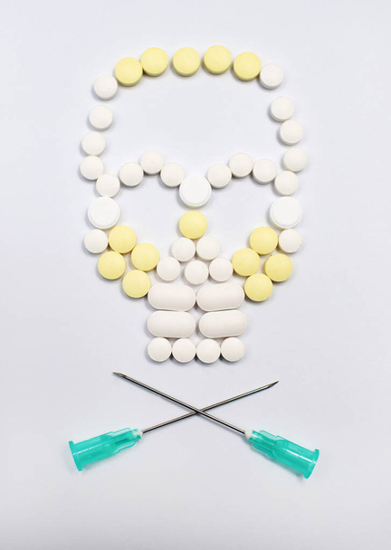 Jolly Roger laid out of multi-colored pills and two crossed needles - Photo, Image