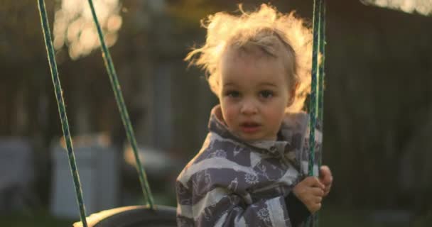 A slow motion happy little boy swinging on a swing. - Footage, Video