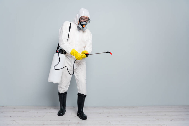 Full body photo of professional specialist guy disinfectant cleaning public transport during pandemic spraying surface wear white hazmat protective suit isolated grey color background - Foto, Imagem
