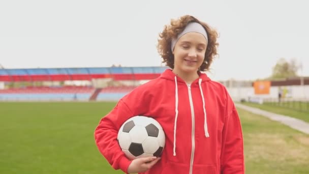 Elinde futbol topu olan gülümseyen genç bir kız futbolcunun portresi. - Video, Çekim