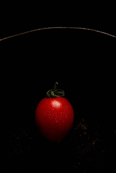 Red fresh healthy tomato isolated on a black cuisine pan - Φωτογραφία, εικόνα