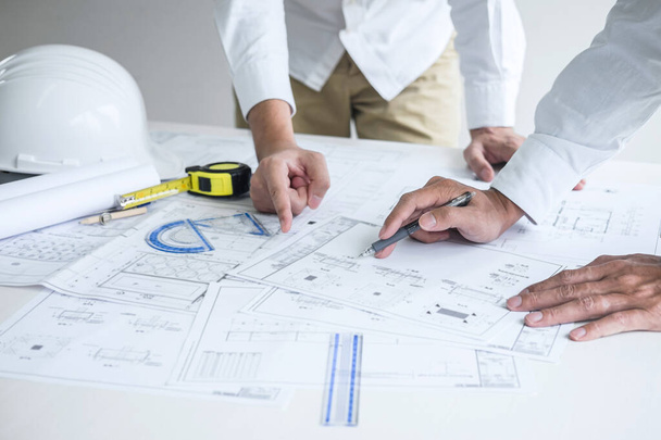 工事現場での建築プロジェクトのスケッチ会議の情報を確認しながら、設計図や建築模型を議論する建築工学や建築家. - 写真・画像