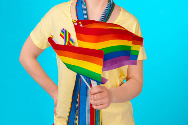 Parlak arkaplanda küçük LGBT bayrağı tutan tanınmayan genç bir kadın. - Fotoğraf, Görsel