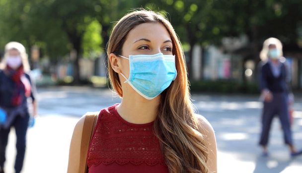 COVID-19 Social Distancing Woman на вулицях міста, одягнена в хірургічну маску проти вірусу SARS-CoV-2. Дівчата з маскою на обличчі відзначають соціальну дистанцію під час хвороби Pandemic Coronavirus 2019.. - Фото, зображення