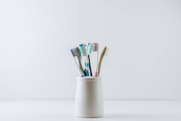 Different types of toothbrushes in a white cup.  - Fotografie, Obrázek