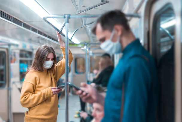 young woman in a protective mask standing in a subway car. - Foto, afbeelding