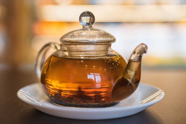 Glass teapot of invigorating fresh fragrant tea on a brown wooden table. Afternoon tea. - Photo, Image