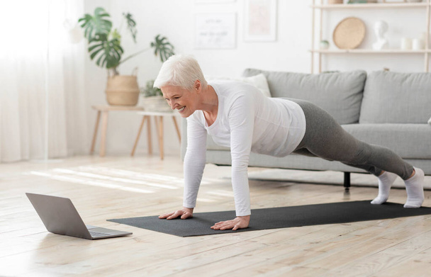 Active Senior Woman Making Plank In Front Of Laptop At Home - Photo, Image