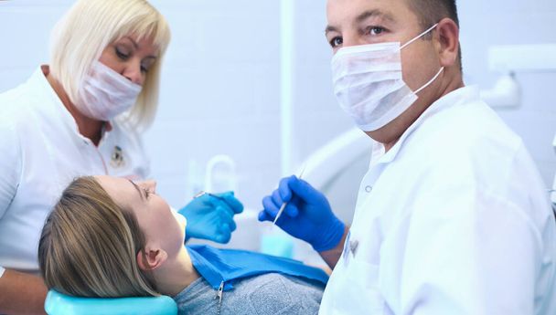 Портрет стоматолога, який лікує зуби пацієнта молодої жінки
 - Фото, зображення