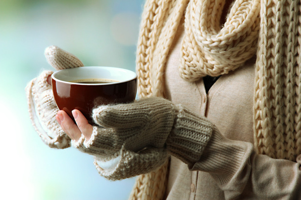 Female hands with hot drink, on light background - Foto, Imagen