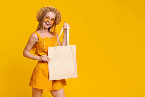 Üres táska a mosolygó lány kezében a nyári ruhákban. - Fotó, kép