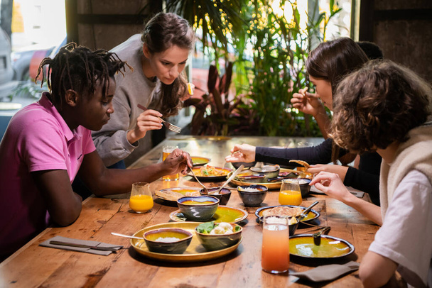 Un grupo de jóvenes amigos compartiendo una comida en un café
 - Foto, Imagen