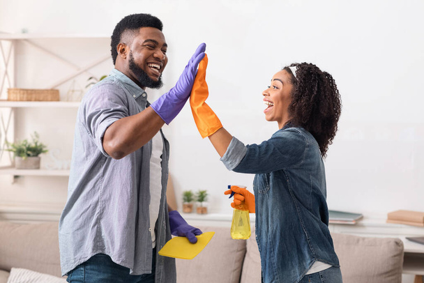 Μαύροι σύζυγοι δίνοντας κόλλα πέντε ο ένας στον άλλο μετά την άνοιξη-καθαρισμού σπίτι - Φωτογραφία, εικόνα