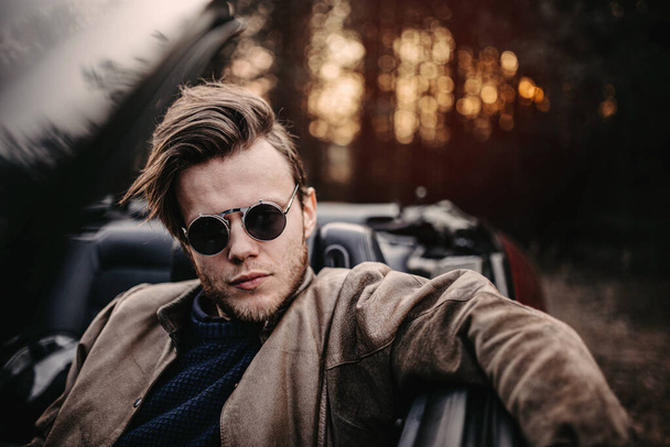 young male driver in sunglasses in a convertible in the summer at sunset. travel concept - Foto, Imagen