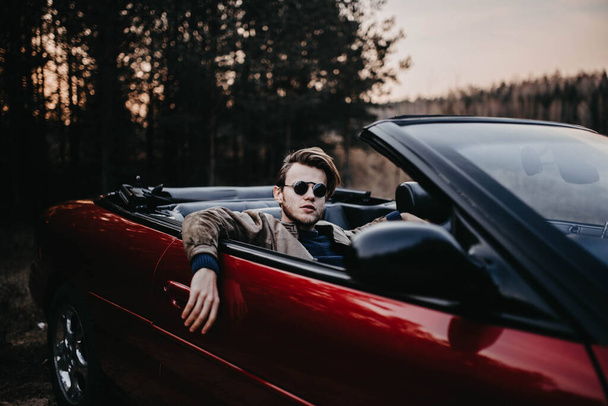 young male driver in sunglasses in a convertible in the summer at sunset. travel concept - Φωτογραφία, εικόνα