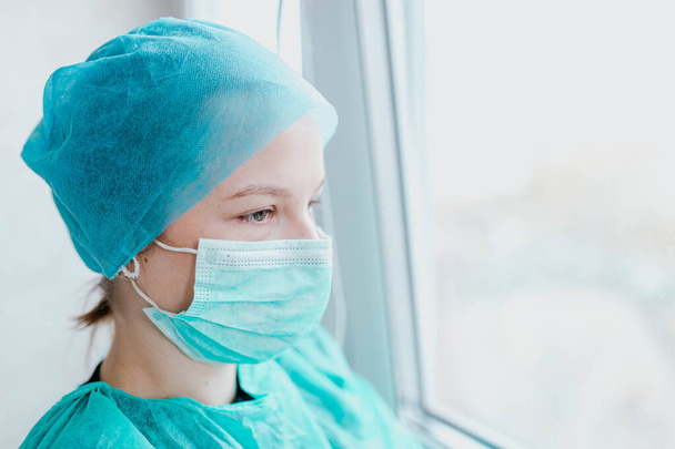молодая женщина врач-интерн в медицинской маске и униформе. Портрет молодого специалиста
 - Фото, изображение