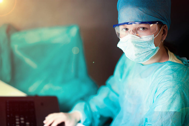 Жінка-лікар в уніформі, окулярах і масках працює зосереджено в лікарні. портрет хірурга
 - Фото, зображення