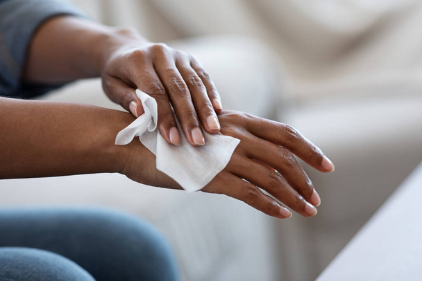 Lingettes antibactériennes. Femme africaine désinfecter les mains avec des tissus humides à la maison
 - Photo, image