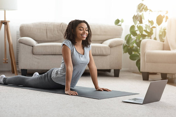 Fille noire pratiquant le yoga à la maison avec ordinateur portable, Regarder des tutoriels en ligne
 - Photo, image