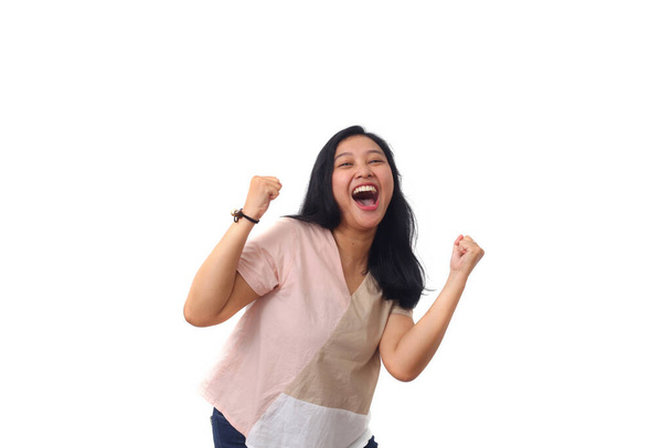 Gyönyörű fiatal ázsiai lány ünnepli sikerét, miközben sikoltozik és mindkét kezébe szorítja. Fehér alapon elszigetelve - Fotó, kép