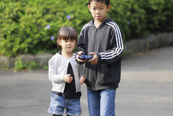 Japán testvér és testvér operationg rádió vezérlés (10 éves fiú és 5 éves lány) - Fotó, kép