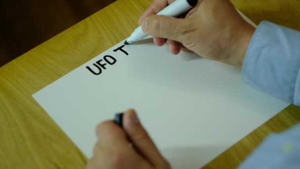 ein Mann schreibt auf Papier und zeichnet verschiedene UFOs - Filmmaterial, Video