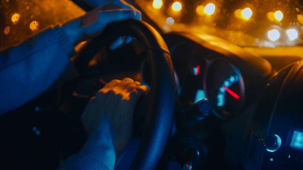 Молодой человек за рулем автомобиля ночью - держит руль у центра
 - Фото, изображение