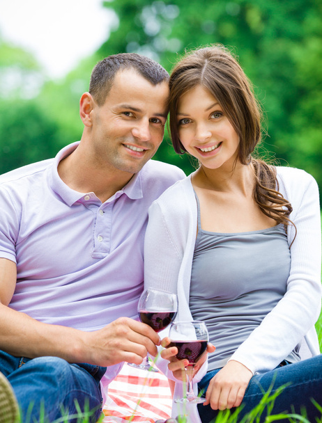 Young couple drinks wine in park - Foto, imagen