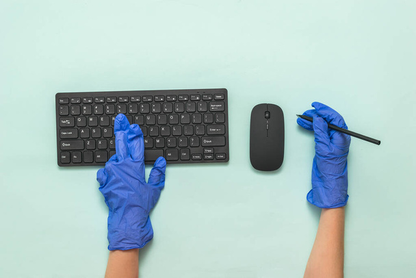 Blue-gloved hands with a wireless keyboard, mouse and pencil. - Photo, Image