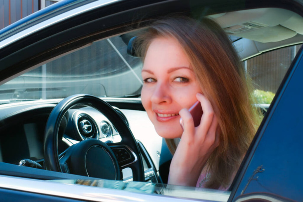 Blonde in the car happy. talking on the phone in the car. Happy businesswoman - Foto, imagen