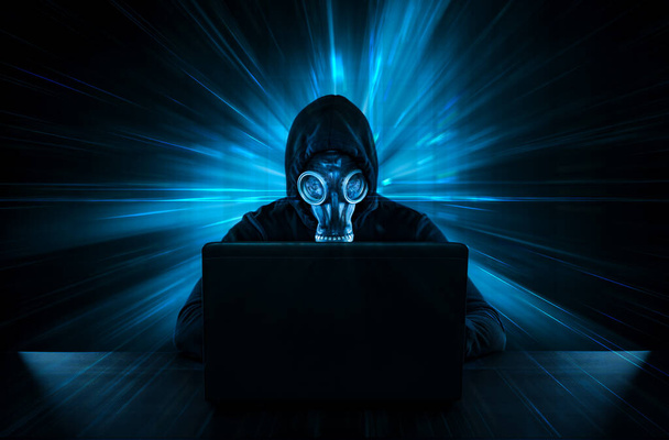 Mannelijke dief in gasmasker stelen van gegevens van de computer - Foto, afbeelding