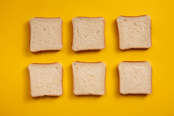 Top näkymä neliön paloja leipää. Kuusi neliön paahtoleipää, valkoista leipää kirkkaan keltaisella pohjalla
. - Valokuva, kuva
