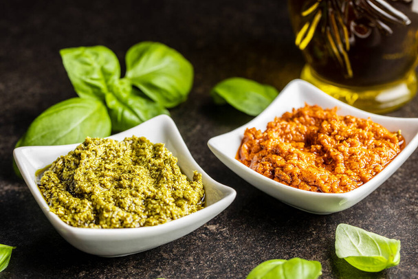 Green basil and red tomato pesto dip sauce  and basil leaves on black table. - Foto, Imagen