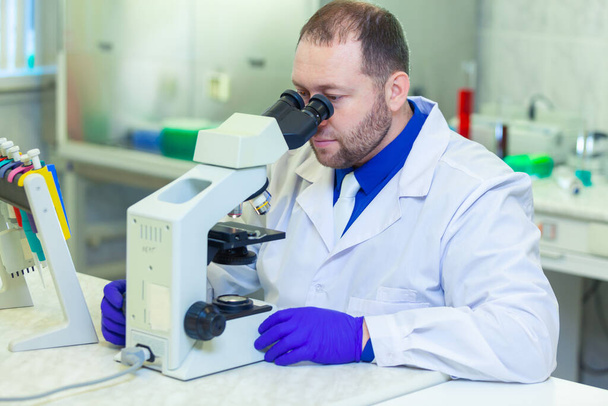 Specialist looking through microscope performing scientific research in a laboratory. Urine test. COVID-19. COVID Coronavirus - Foto, immagini