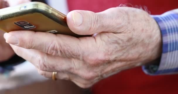 Akıllı telefonu tutarken yaşlı insanların ellerini yakın plan çekiyoruz. - Video, Çekim