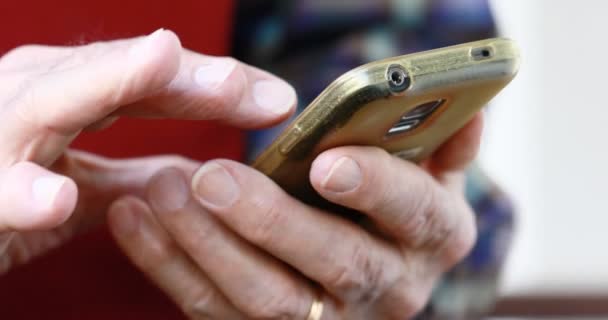 close-up van de handen van de oude persoon omgaan met een smartphone - Video
