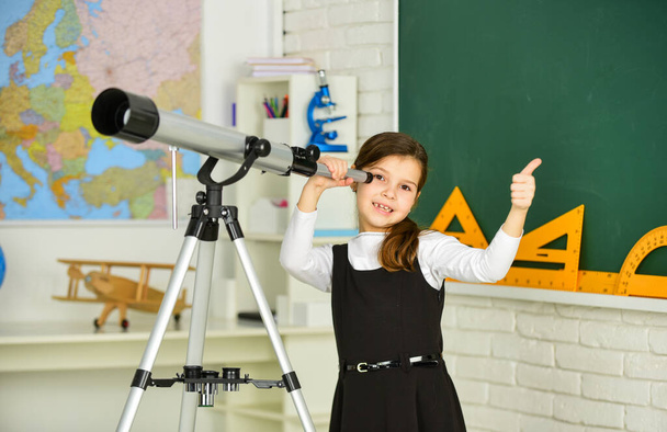 Observation concept. Astronomy and Astrophysics. Stars and galaxies. Study telescope. School astronomy lesson. School girl looking through telescope. Telescope tripod in classroom. School hobby club - Foto, immagini